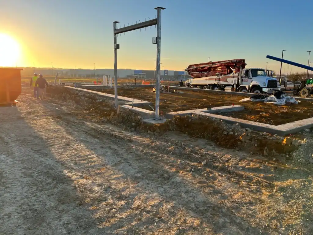 Construction site with heavy machinery and workers at sunset.